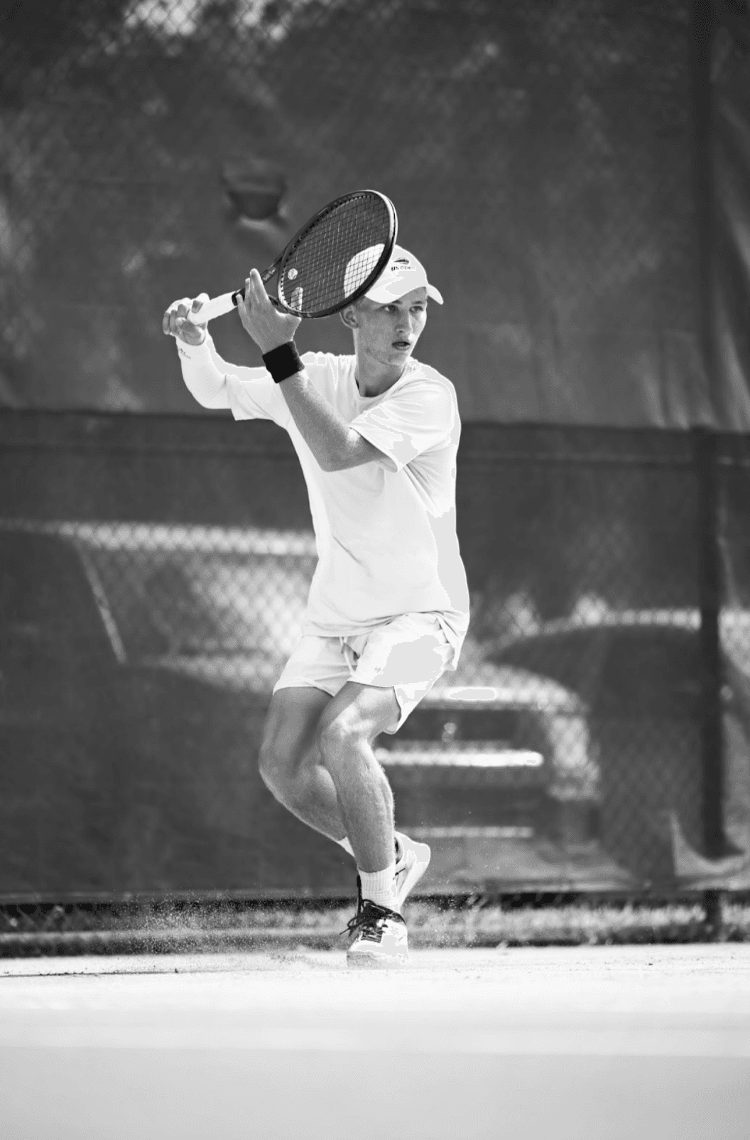A tennis player loading into a two-handed backhand, in black and white